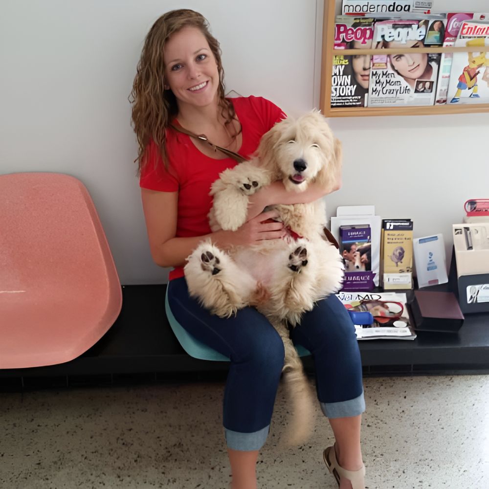 A women seated on a chair holding a dog